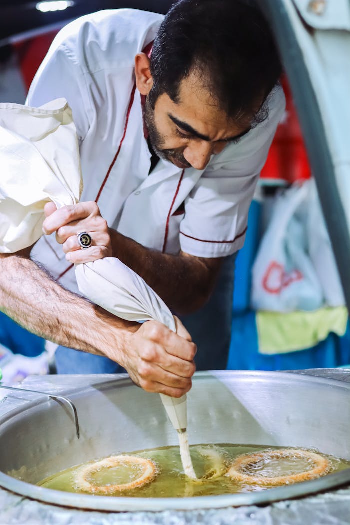 A chef skillfully preparing traditional Turkish Halka Tatlisi dessert in a frying pan.
