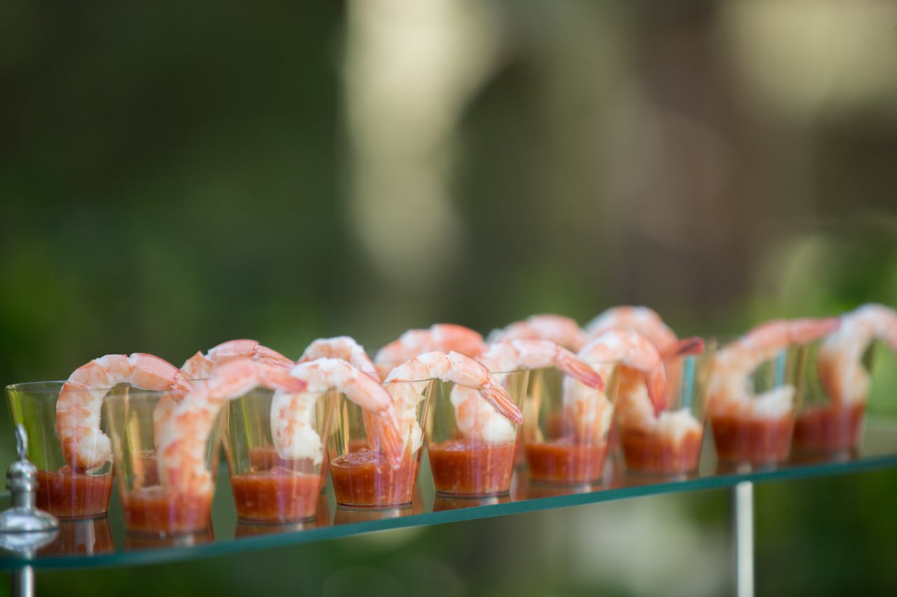 brand-01 Close-up of shrimp cocktail appetizers arranged elegantly on a glass table, perfect for gourmet food presentations.
