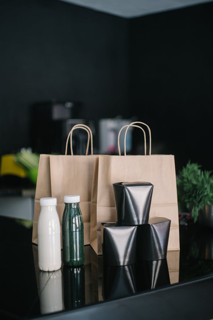 our-story Stylish delivery setup with paper bags and bottles on a black table.