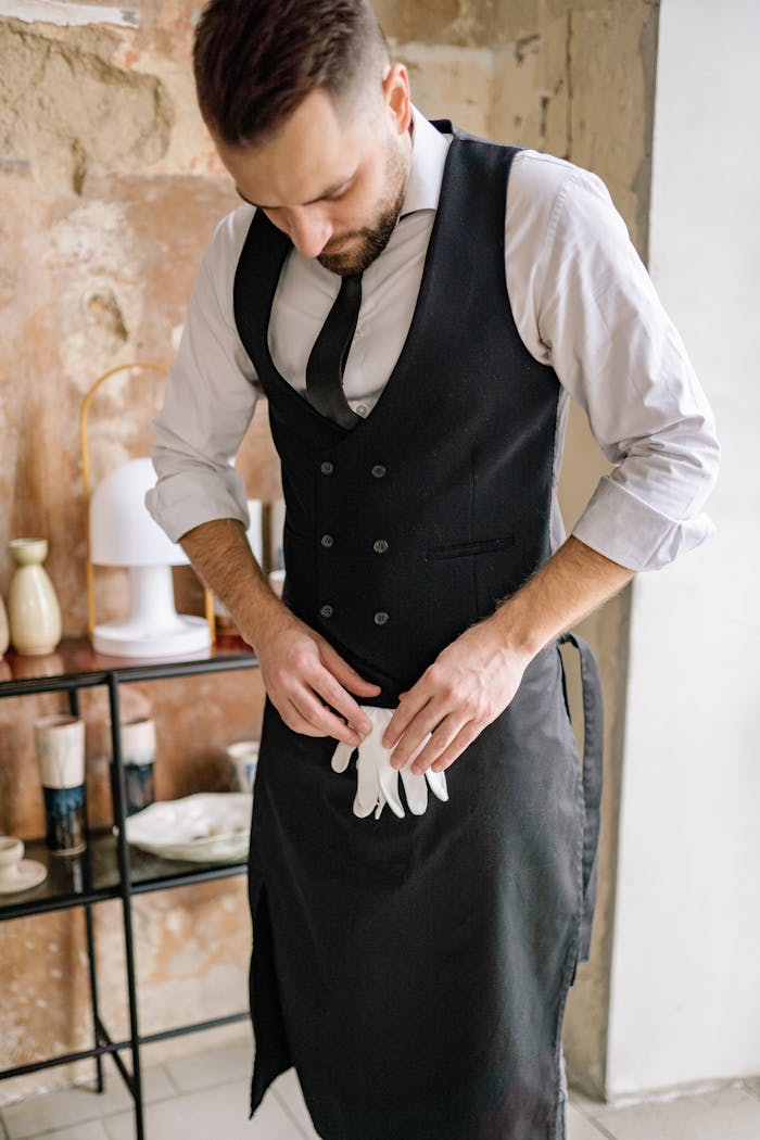 brand-02 Young waiter putting on apron in a rustic restaurant setting.